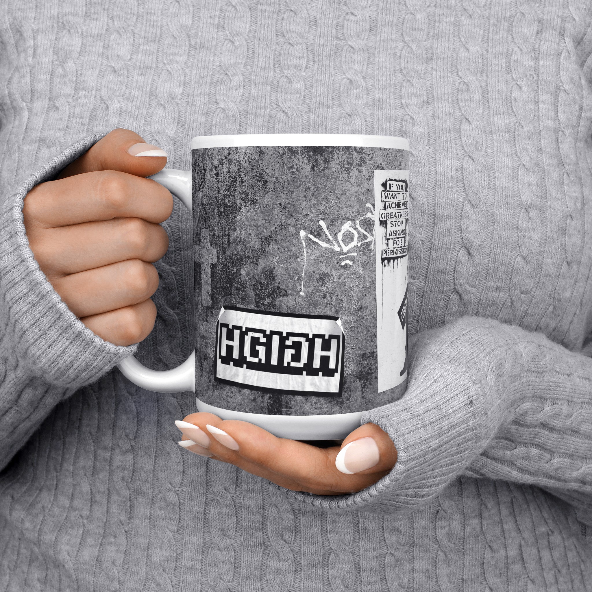 Close-up of a woman in a cozy gray pullover holding the Achieve Greatness Coffee Mug, 11oz, side view with the handle on the right, embodying a blend of urban flair and inspirational energy.