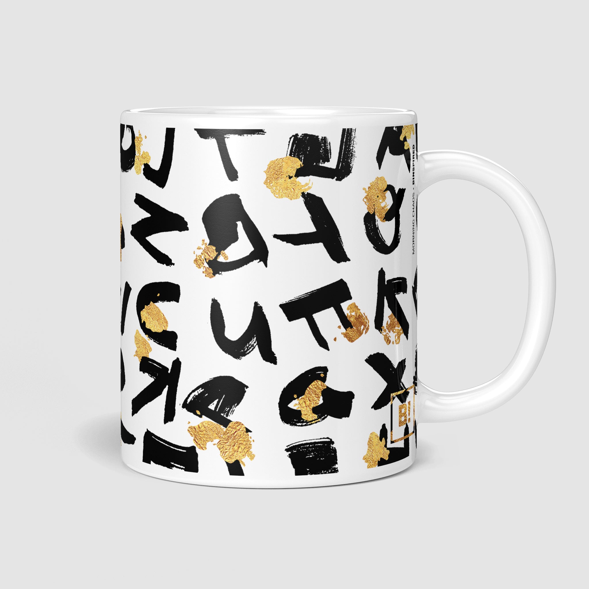 11oz coffee mug, side view with handle on the right, featuring a bold black random lettering design and luxurious golden splatter, blending elegance and creativity.